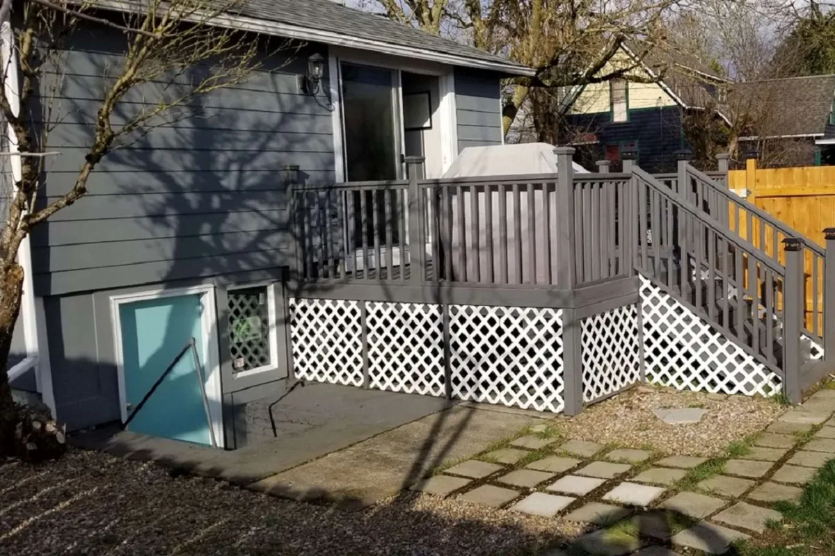 A welcoming deck area connected to the home, featuring stairs, charming lattice work, and an inviting back door. The sunlit space is ideal for enjoying morning coffee or relaxing outdoors, with the direct deck access suggested by the primary suite’s layout.