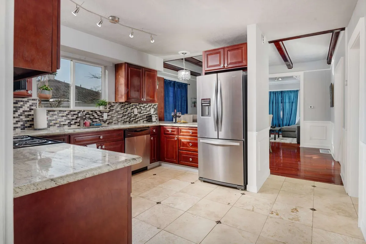 A stylish, open kitchen with a prominent kitchen island, stainless steel appliances, a mosaic backsplash, and a large window that brightens the space. The setting suggests an ideal spot for preparing meals and hosting family gatherings.