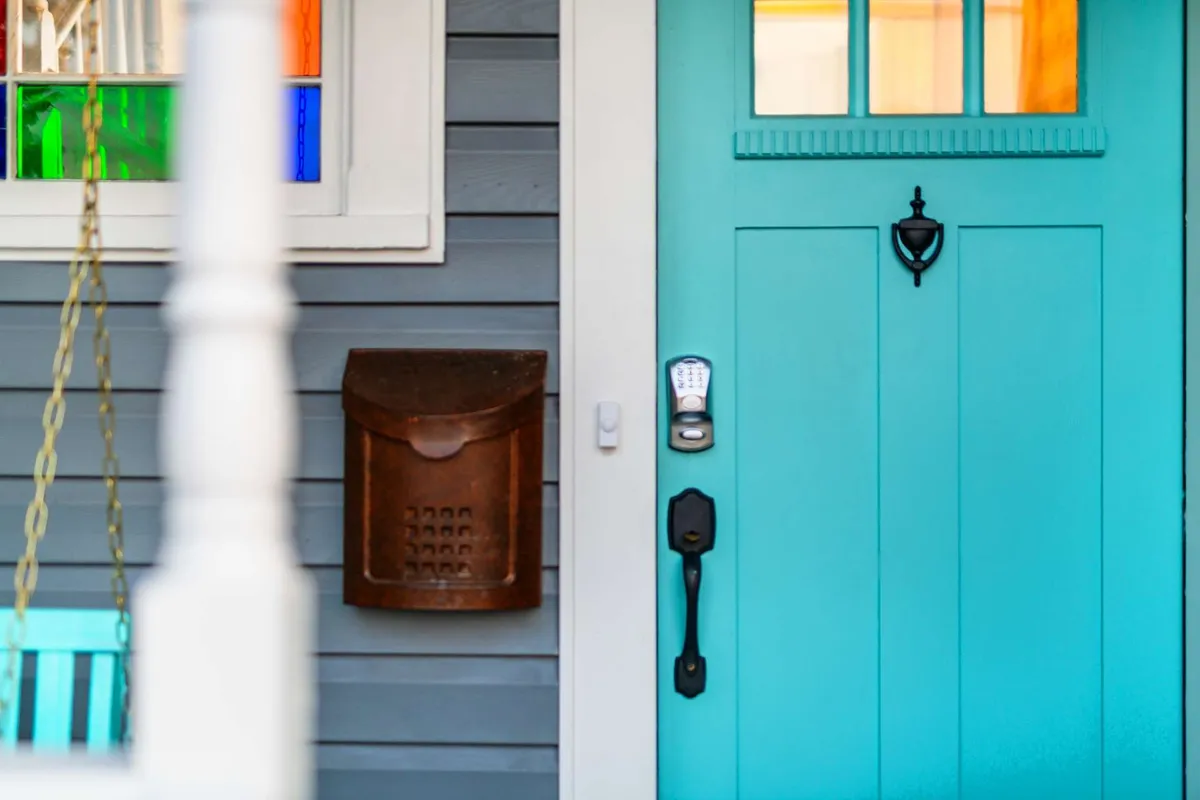 A charming exterior view featuring a turquoise door with a vintage mail slot and multicolored window panes, inviting guests into the property and offering a welcoming first impression.